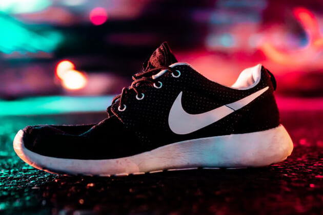 ネオンに照らされながら片方だけ置かれている白と黒のナイキの靴